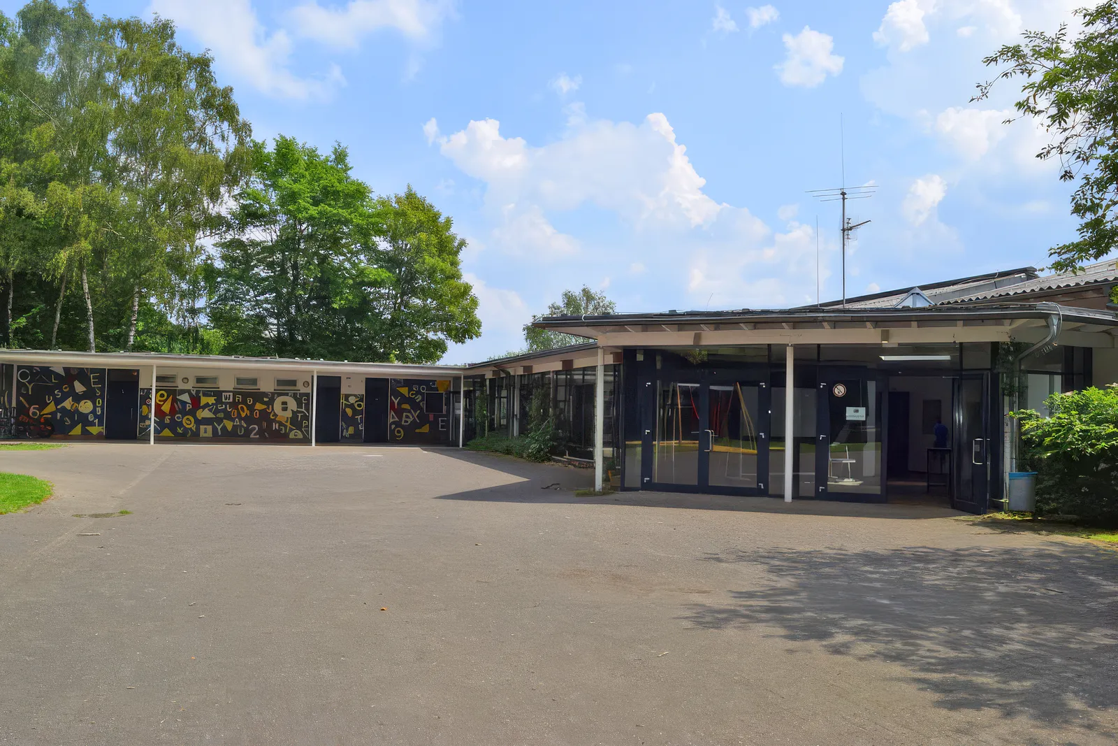Schulgebäude der GGS Auf dem Höchsten mit Schulhof, Eingang und Mosaikwand